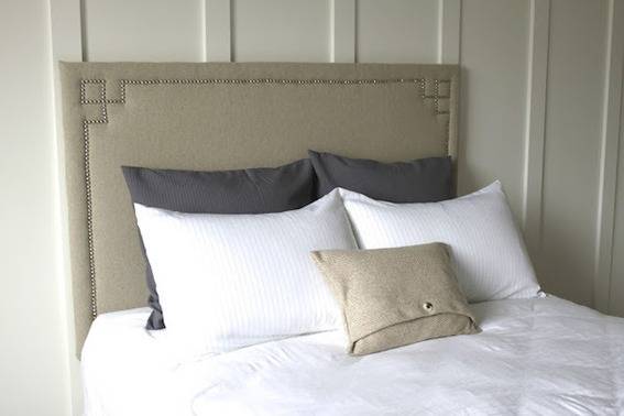 A white bed has a pewter headboard.