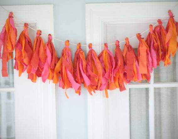 A string of red and orange decorations are strewn over a white door.