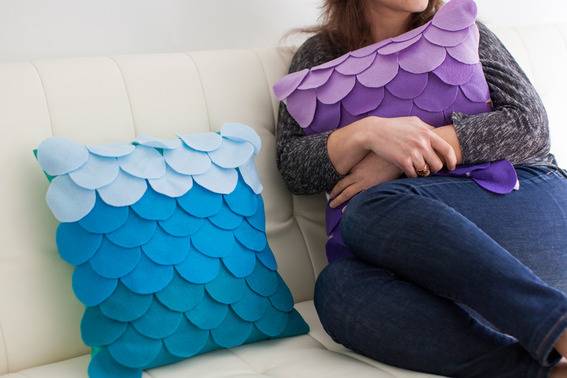 Woman sitting on a white couch, holding a purple pillow.