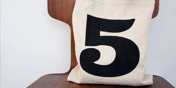 "Number five printed bag is on the wooden chair."