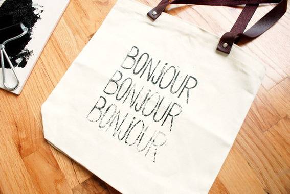 A white tote bag printed with BONJOUR three times.