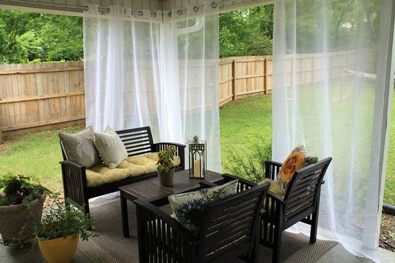 An outdoor sitting area with curtains hanging.