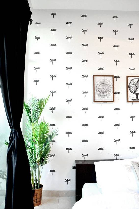 A plant is sitting in the corner of a room with a black and white wall paper.