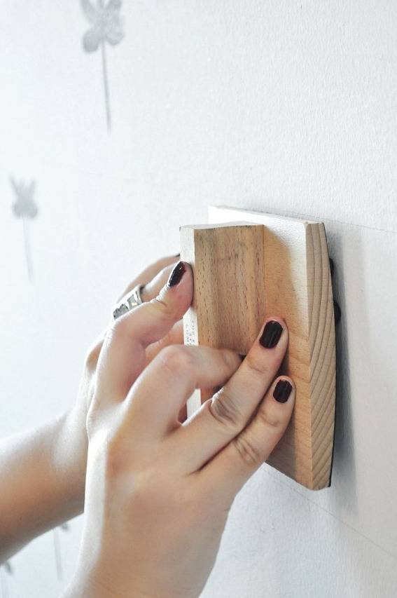 A person uses a wooden stamp to pattern a wall.