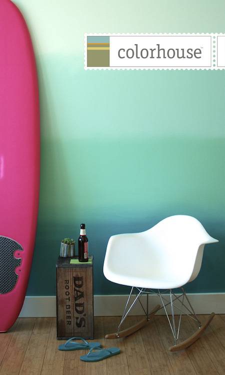 Modular white chair and magenta surfboard in front of wall pained with blue and aqua ombre effect.