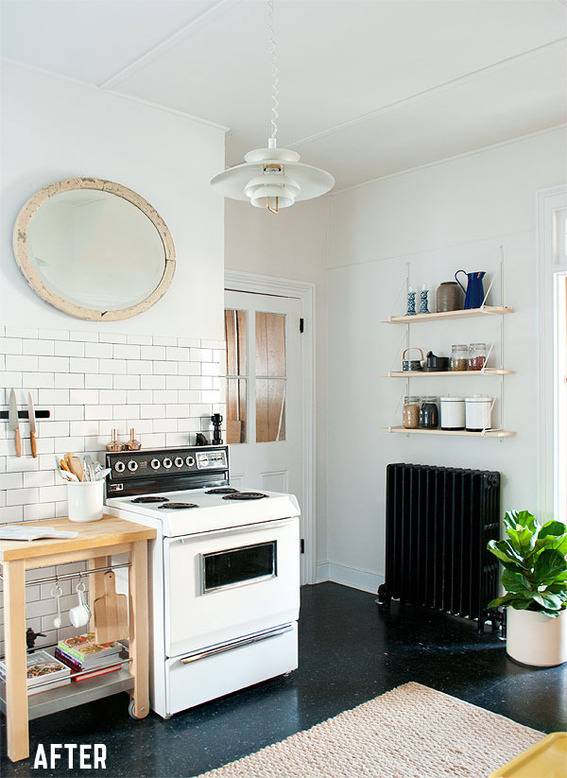 White and black kitchen with subway tiles, a stove, a spice rack, and a large mirror.