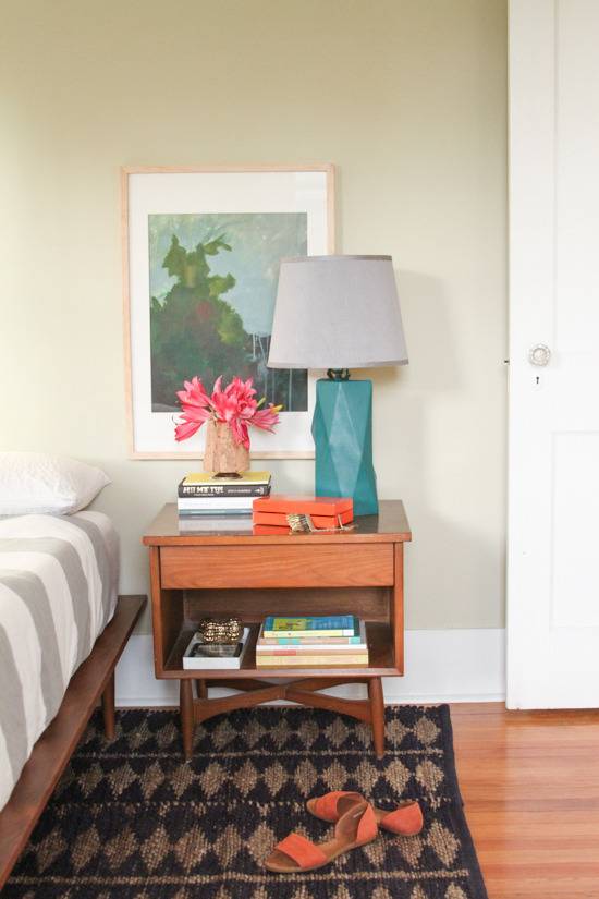 A bedroom has colorful flowers and a lamp on a desk.