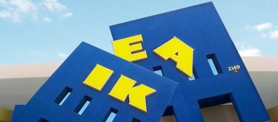 A broken IKEA sign with yellow lettering and a blue building.