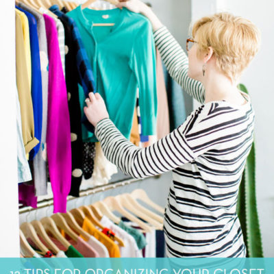 Woman is putting a blue cardigan back into the closet.