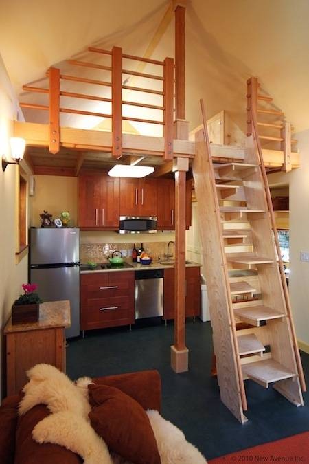A loft with a whie latter and a kitchen under the loft.