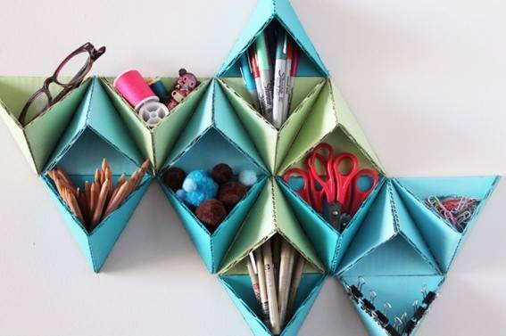 A green and blue origami shelf is decorative and has items in the pockets.