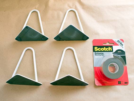 A pair of white hangers lays next to a package of scotch tape.