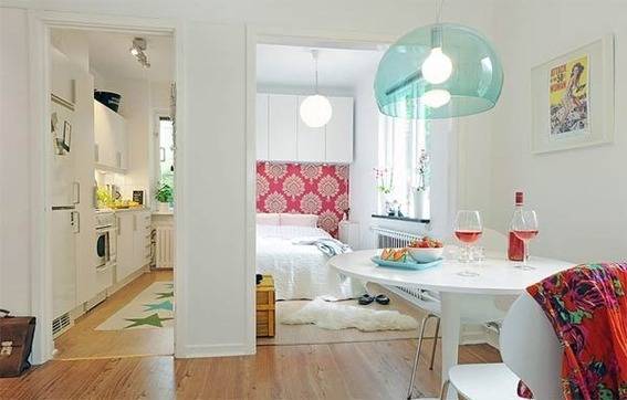 The kitchen sits on the left of the bedroom area in a studio apartment with bright interiors and colorful decors.