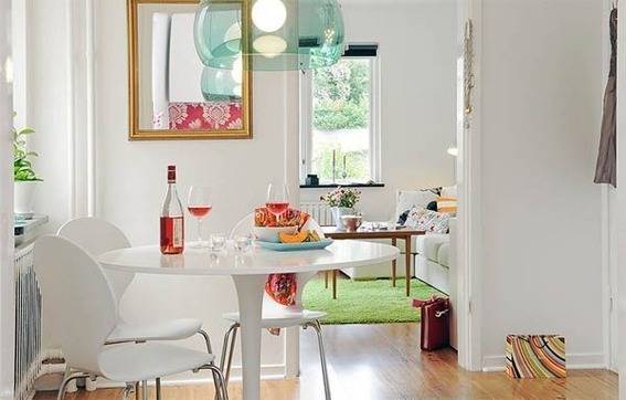 A kitchen has a small white round table and a mirror.