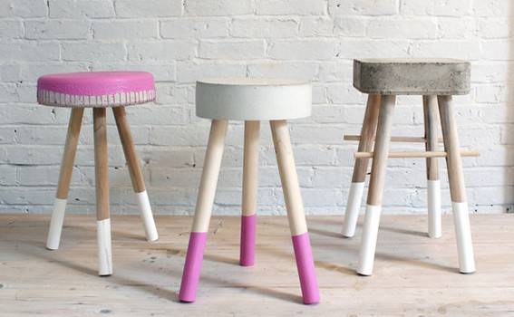 Three stools styled with the colors pink, white, and grey.