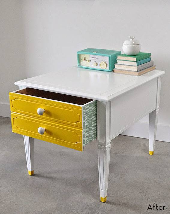 A desk with yellow drawers has blue books on it.