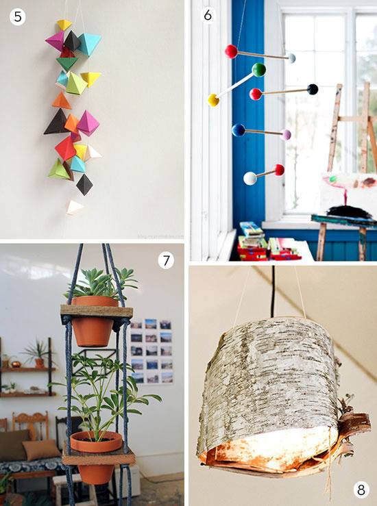 A group of colored paper triangles hanging from the wall, Two large clay pots in a hanging planter, a mobile with several white dowels with colored balls on the ends and a rustic grey pendulant light.