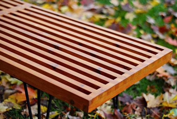 A wooden bench sits outside in the leafy grass.