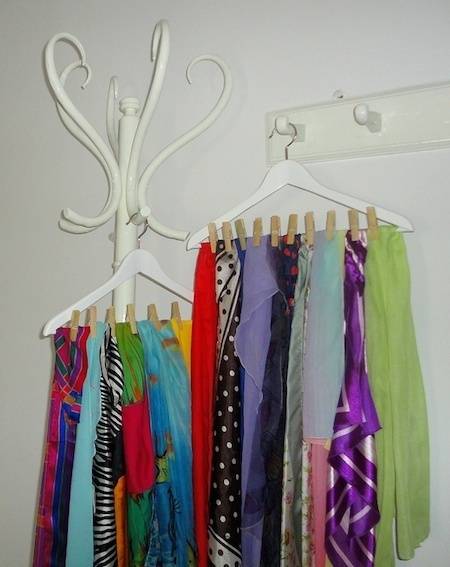 Various women's clothing lined up on clothespins, suspended over hangers on a wall-mount.