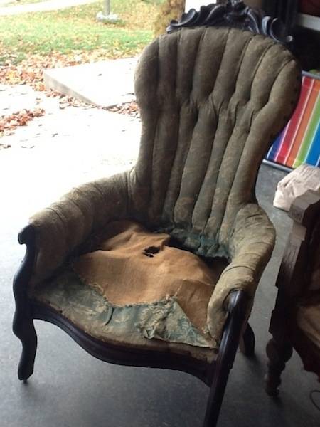 A dirty green chair in a garage need reupholstering.