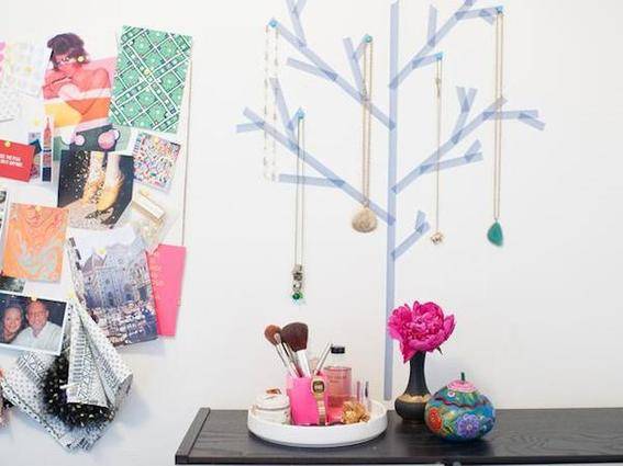 A table with make up on it in front of wall decorated with pictures and a holiday tree.