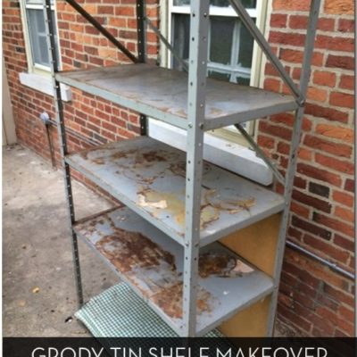 Rusted tin shelf with five levels sits outside a brick building.