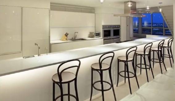 Bar stools line an countertop island in a modern kitchen in a high-rise.