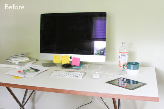 A computer monitor, keboard, a mouse, a bottle of water and a green and white mug on a white table.
