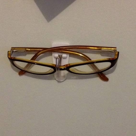 A pair of brown eyeglasses sitting on an eyeglasses stand.