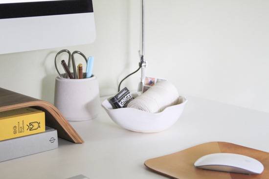 A desk has a mouse and many office items on it.