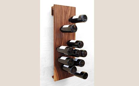 Ten wine bottles stuck stem first into a wall board.