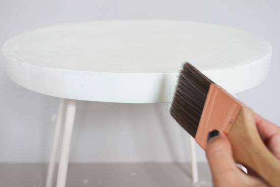 Someone painting a small white endtable.