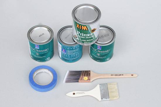 Four paint cans, a roll of blue painters tape, and two paint brushes.