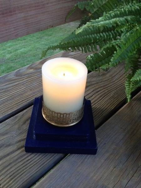 A small candle sits on a dark blue base on a wooden surface.