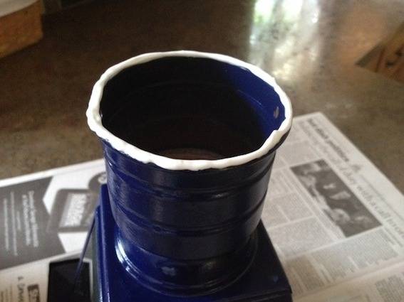 A blue cup with a white rim on a newspaper.