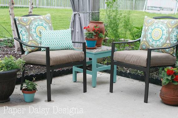 A patio has two chairs and a teal end table.