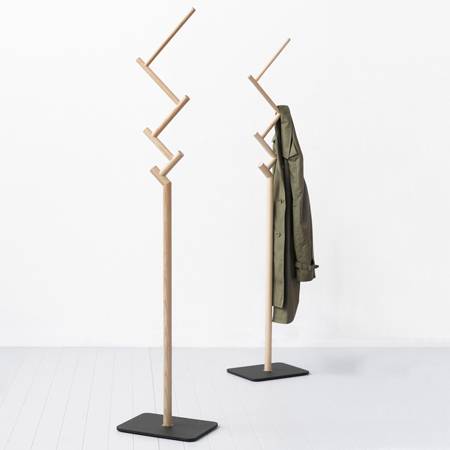 A coat is hanging from and next to a coat stand.