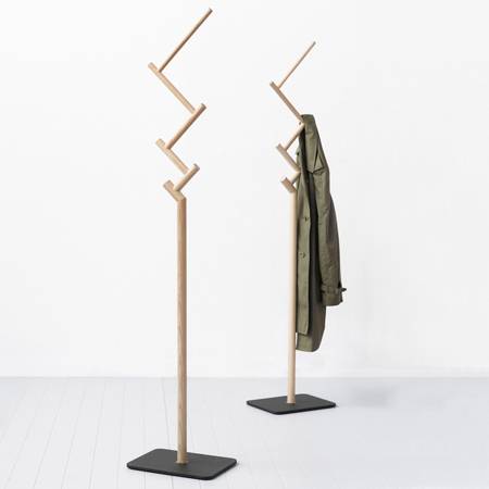 A coat is hanging from and next to a coat stand.