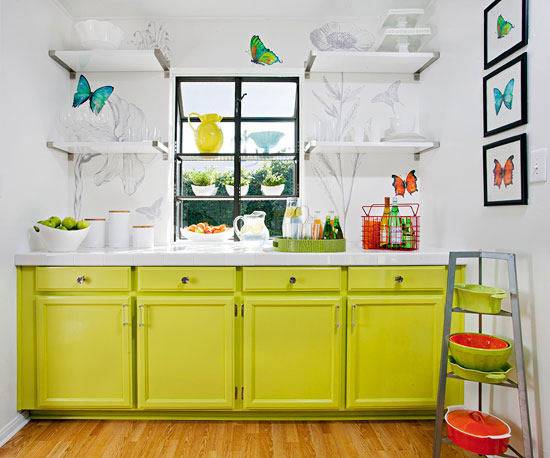 A kitchen with butterfly art and yellow cabinets.