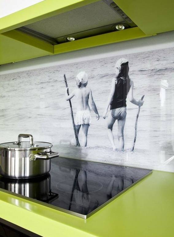 A green kitchen has a picture on the backsplash.