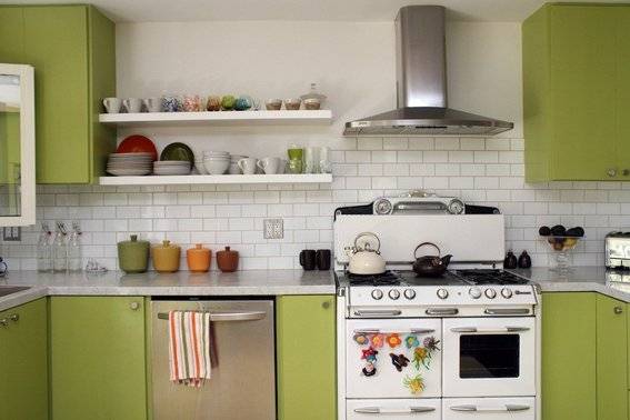 A kitchen has asparagus green cabinets next to a white oven.