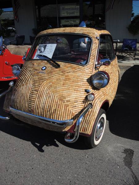 A small antique car is light brown with colored streaks.