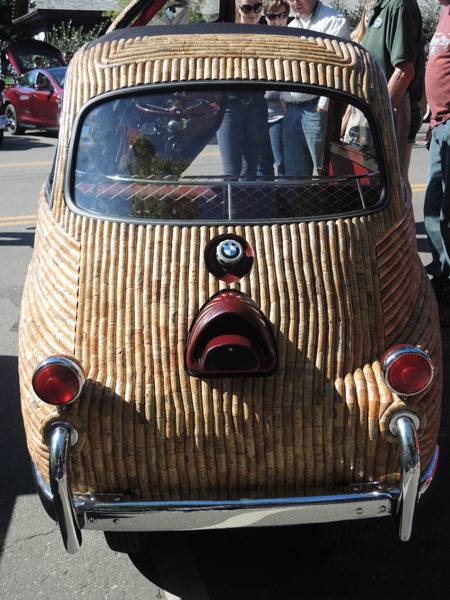 A small antique car has a wooden exterior with ridges.