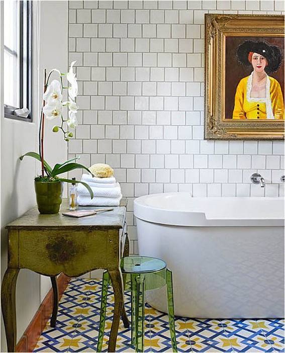 A tub is sitting under a portrait of a woman in a white room.