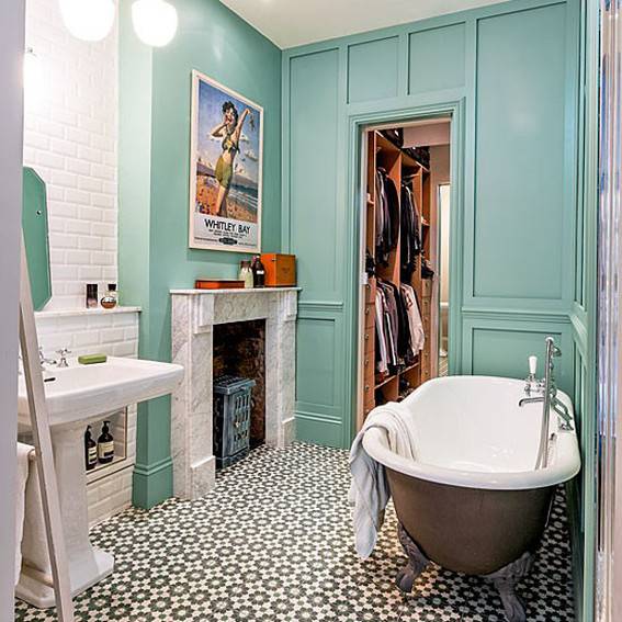 A bathroom has a round tub and teal cabinets.