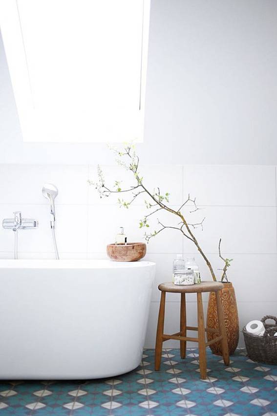 Clean white bathroom with a large tub, blue tile floor, and wooden stool.