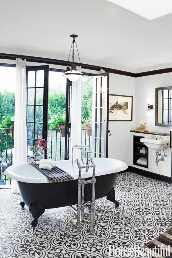 A large room has a black and white tub in the middle.