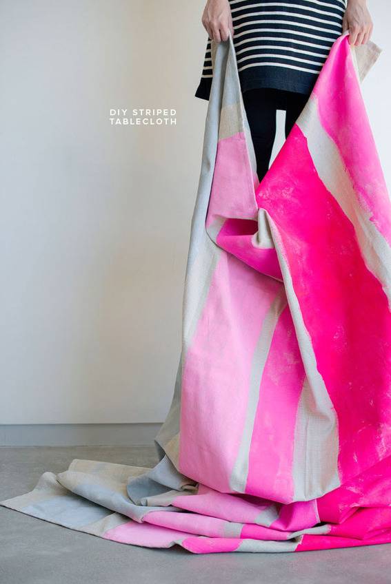 A person in a black and white striped shirt holds up a pink and white towel.