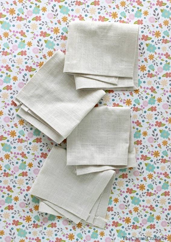 Four folded napkins on a brown, pink and green flowered background.