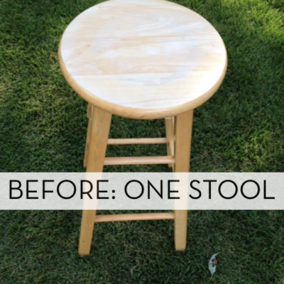 One raw wood stool with a round seat on a lush green lawn.